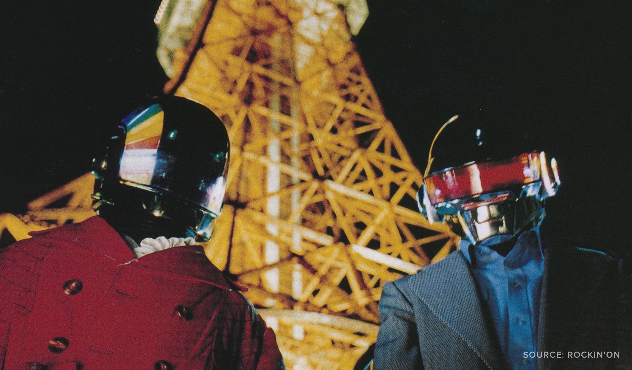 A photo of Daft Punk in front of Eiffel Tower at night.